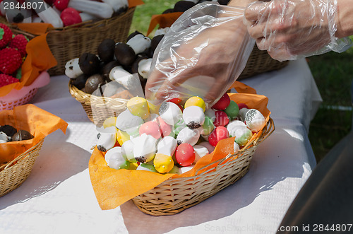 Image of hand takes baked pastry mushrooms from basket 