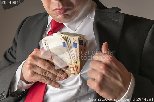 Image of Businessman putting money in pocket