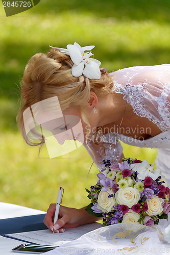 Image of beautiful blonde smiling bride signed contract