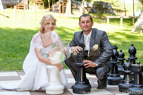 Image of beautiful young wedding couple and outdoor chess