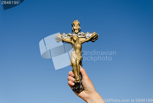 Image of metal cross crucified christ in hand on blue sky  