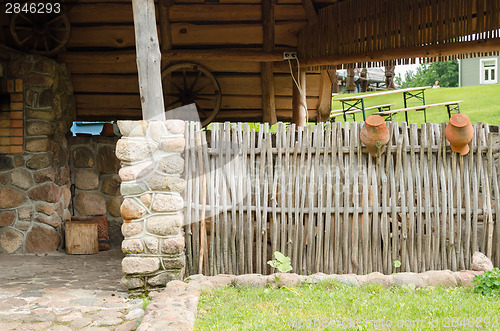 Image of homestead house and wicker fence with old pots 