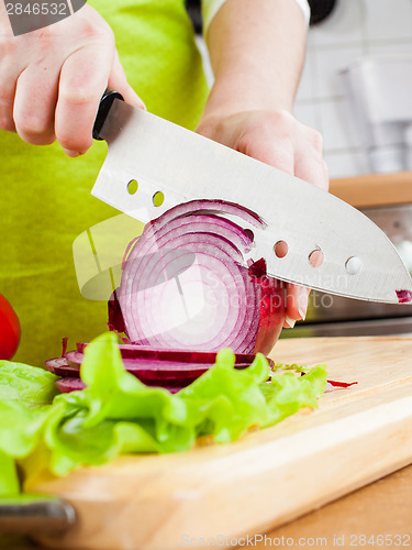 Image of Woman's hands cutting bulb onion