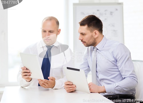 Image of two serious businessmen with tablet pc in office