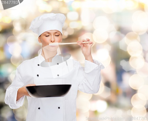 Image of smiling female chef with pan and spoon