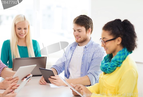 Image of smiling team with table pc and laptop in office