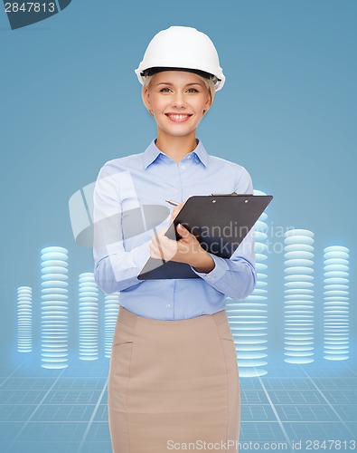 Image of smiling businesswoman in helmet with clipboard