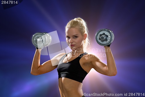 Image of sporty woman with heavy steel dumbbells