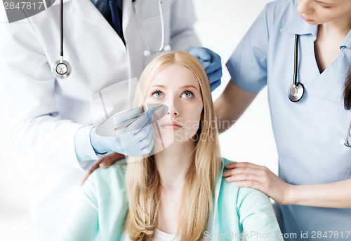 Image of plastic surgeon and nurse with patient