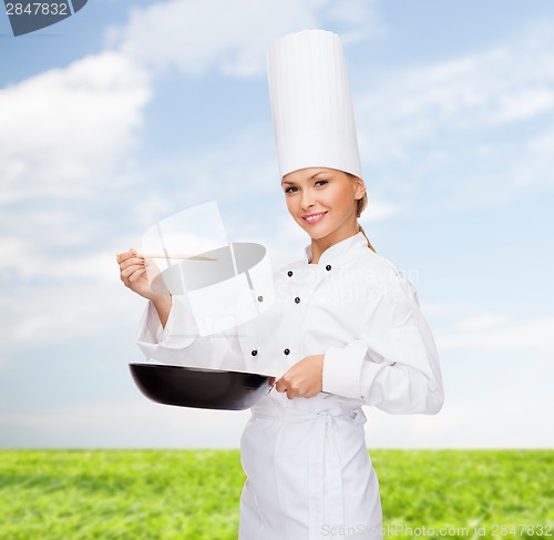 Image of smiling female chef with pan and spoon