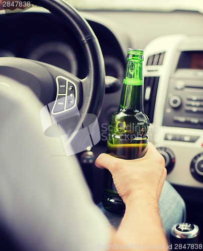 Image of man drinking alcohol while driving the car