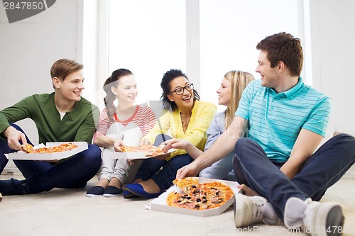 Image of five smiling teenagers eating pizza at home