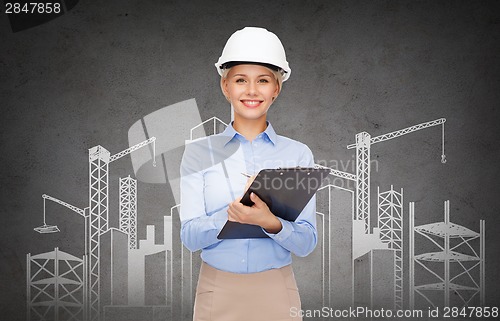 Image of smiling businesswoman in helmet with clipboard