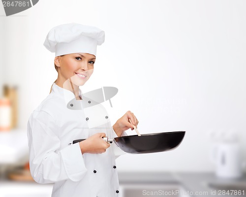 Image of smiling female chef with pan and spoon