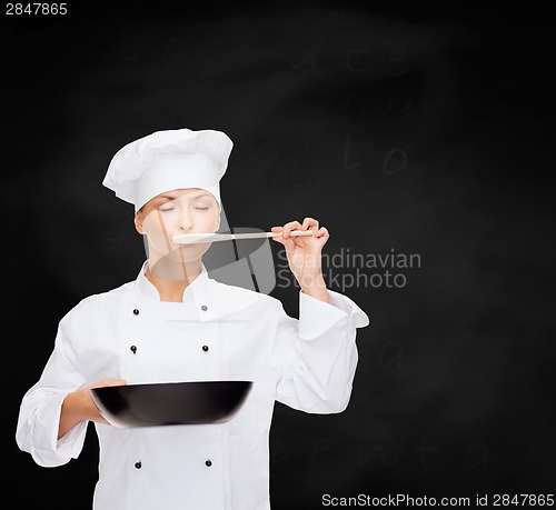 Image of smiling female chef with pan and spoon