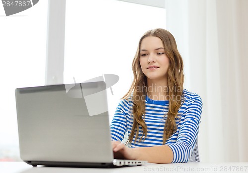 Image of smiling teenage gitl with laptop computer at home