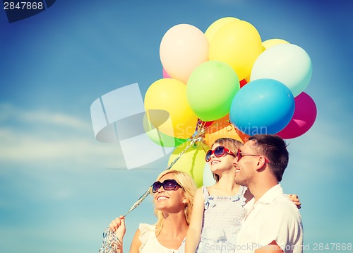 Image of happy family with colorful balloons outdoors