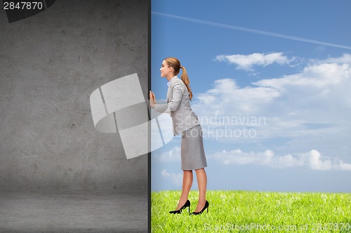 Image of businesswoman pushing away concrete wall