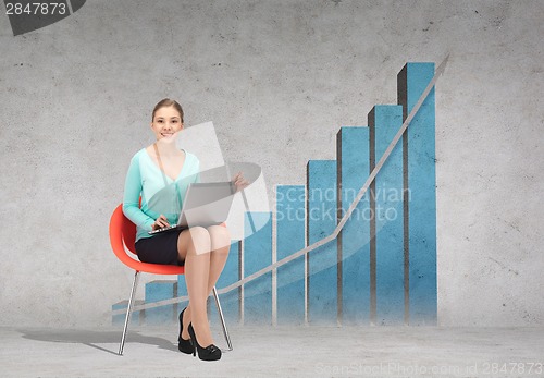 Image of young businesswoman sitting in chair with laptop