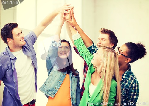 Image of happy students giving high five at school