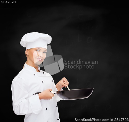 Image of smiling female chef with pan and spoon