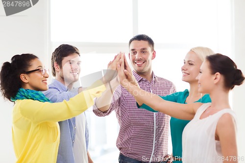 Image of creative team doing high five gesture in office