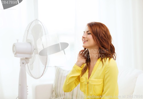 Image of smiling redhead teenage girl with big fan at home