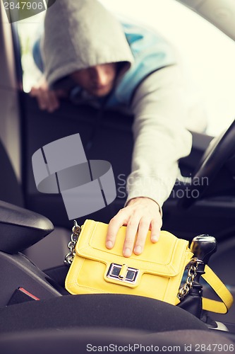 Image of thief stealing bag from the car