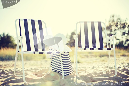 Image of two beach lounges with beach bag and white hat