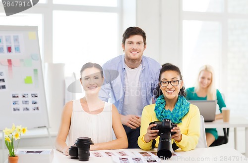 Image of smiling team with photocamera working in office