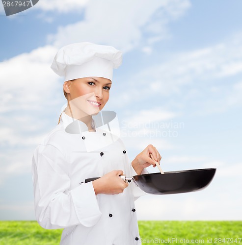 Image of smiling female chef with pan and spoon