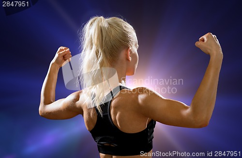 Image of sporty woman from the back flexing her biceps