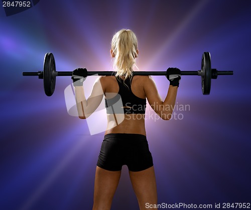 Image of sporty woman exercising with barbell from back