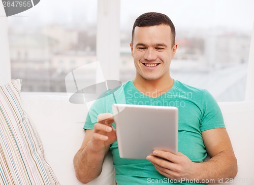 Image of smiling man working with tablet pc at home