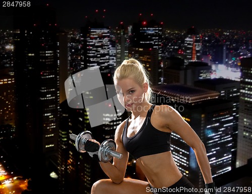 Image of young sporty woman with heavy steel dumbbell