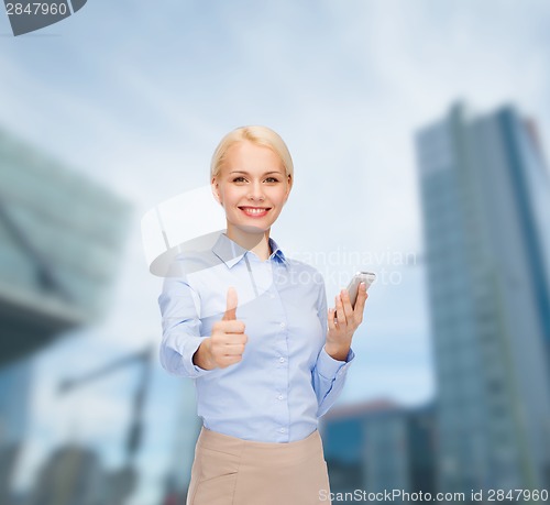 Image of young smiling businesswoman with smartphone