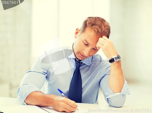 Image of businessman writing in notebook