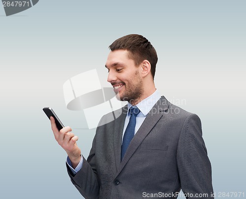 Image of young smiling businessman with smartphone