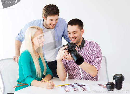 Image of smiling team with photocamera working in office