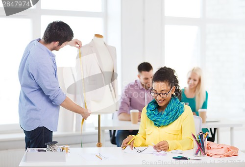 Image of smiling fashion designers working in office