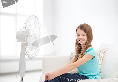 Image of smiling little girl with big fan at home