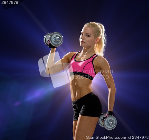 Image of sporty woman with heavy steel dumbbells