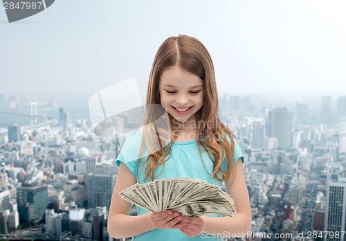 Image of smiling little girl looking at dollar cash money