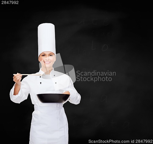 Image of smiling female chef with pan and spoon