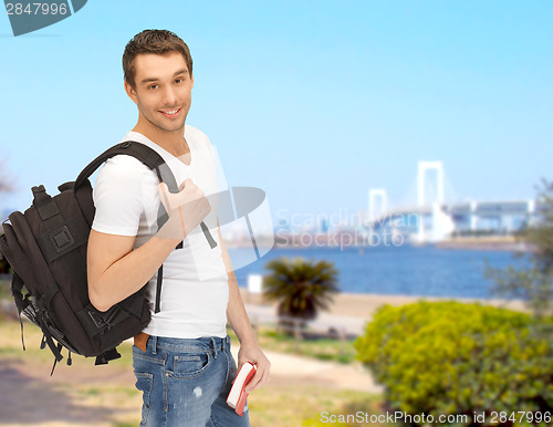 Image of travelling student with backpack and book