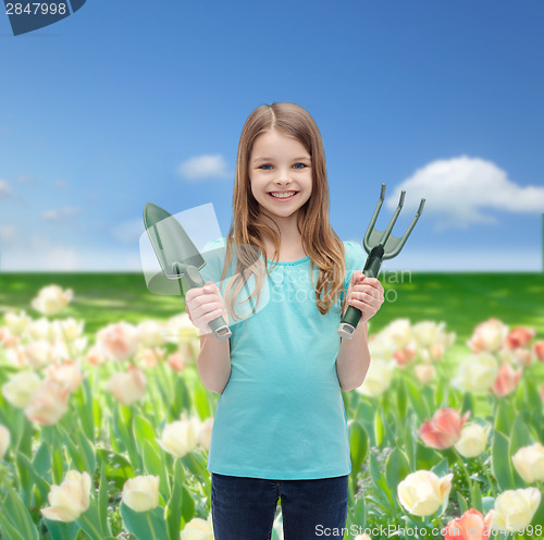 Image of smiling little girl with rake and scoop