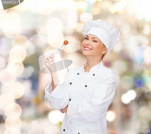 Image of smiling female chef with fork and tomato