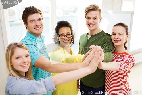 Image of five smiling students giving high five at school