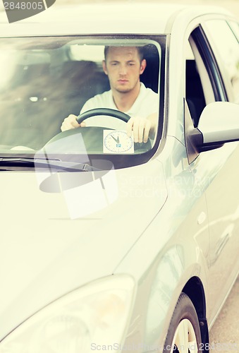 Image of man placing parking clock on car dashboard