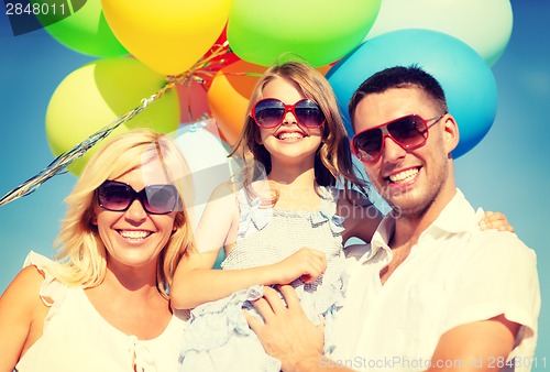 Image of happy family with colorful balloons outdoors